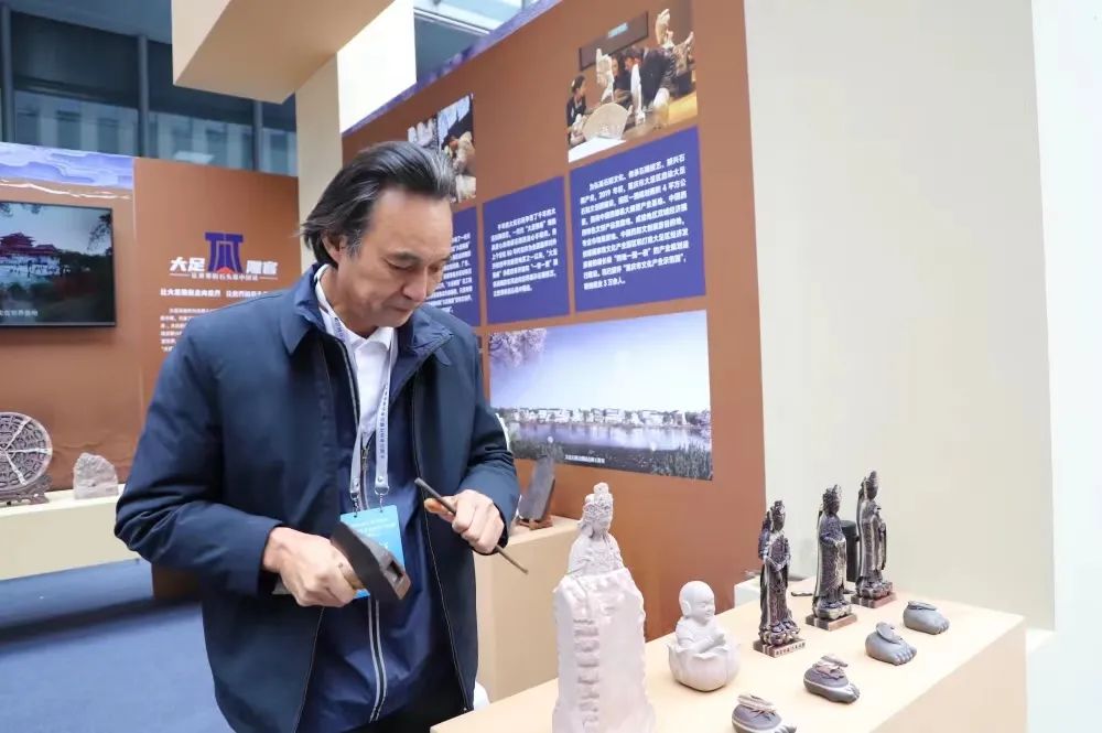 “大足雕客”形象代言人劉能風在參展現場展示精湛的大足石雕技藝。市人力社保局供圖