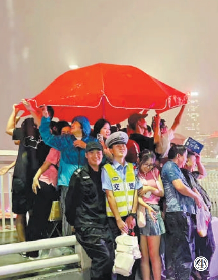 重慶市公安局江北區(qū)分局交巡警支隊(duì)輔警夏英柯在執(zhí)勤中偶遇暴雨，與市民、游客一同避雨。重慶市公安局江北區(qū)分局供圖